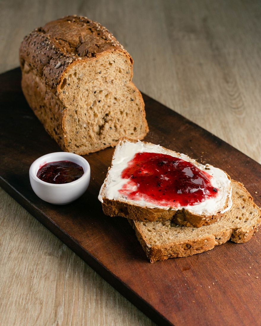 Pan de molde multicereal de masa madre, con una rebanada con queso crema y mermelada