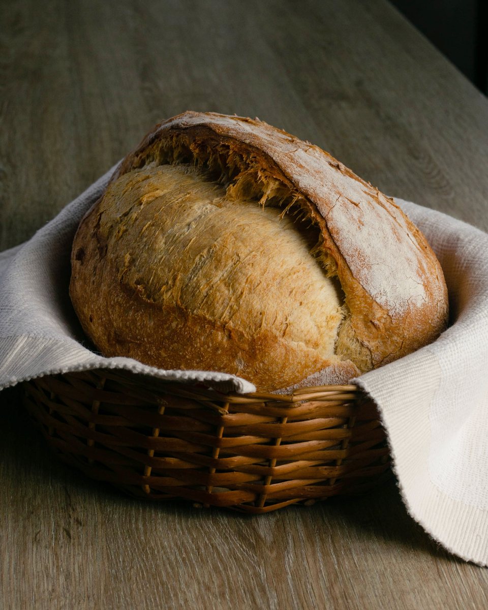 Pan de masa madre de corteza dorada en una canasta de mimbre con un lienzo