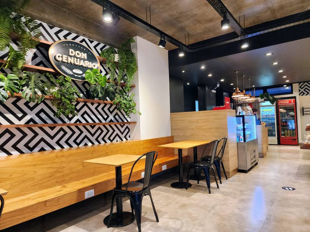 Salón con mesas de madera y pared verde con plantas